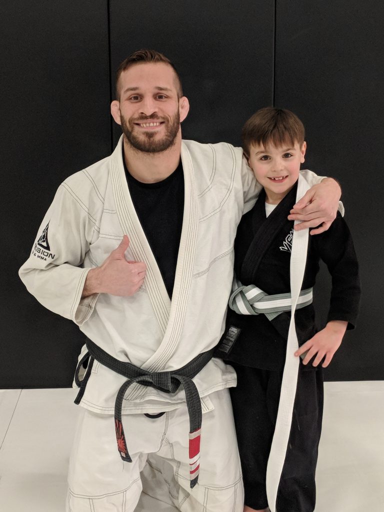 brian kneeling with young student that just received white belt